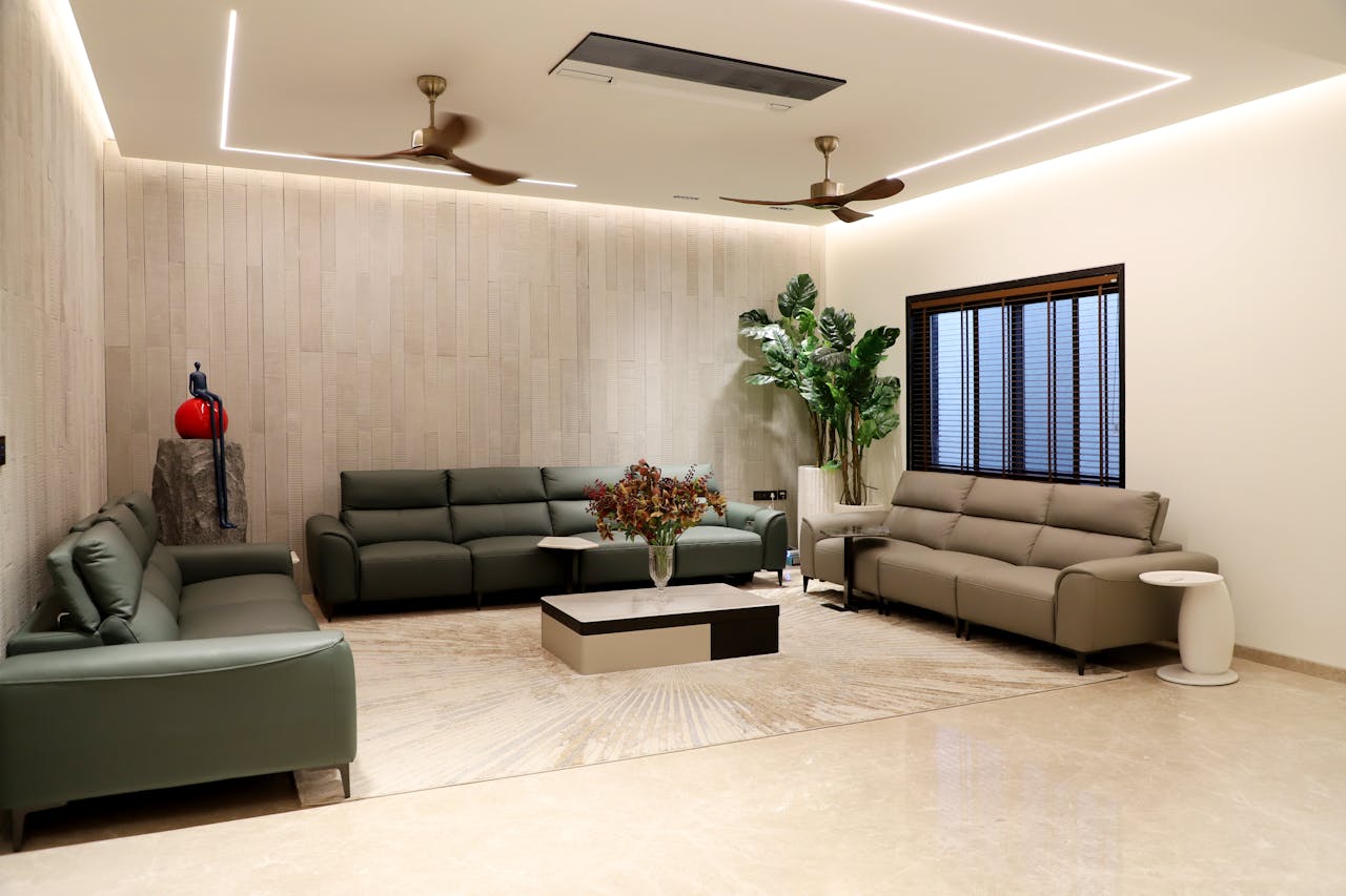 Spacious modern living room featuring green sofas, indoor plants, and minimalistic decor.
